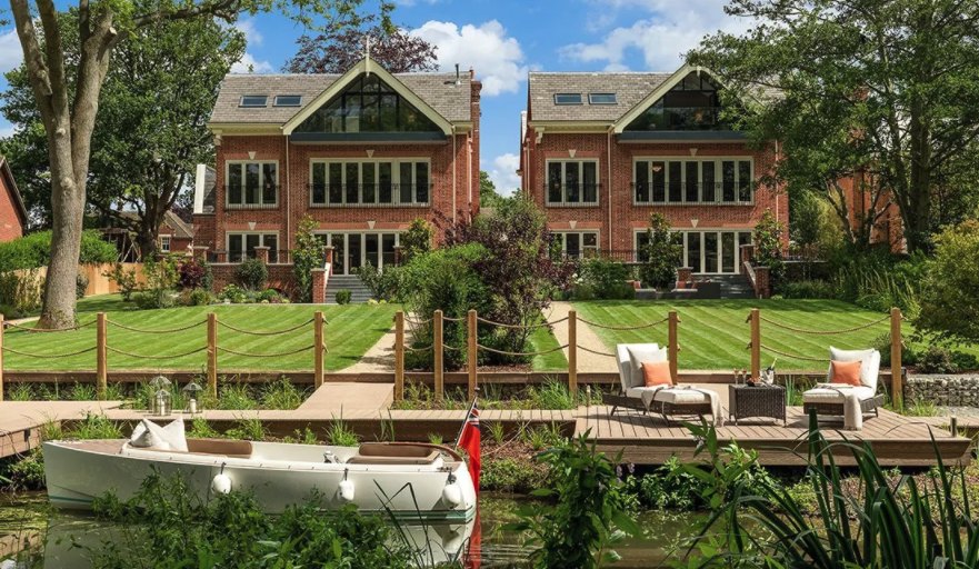 Two brick houses with gardens running down to a river mooring